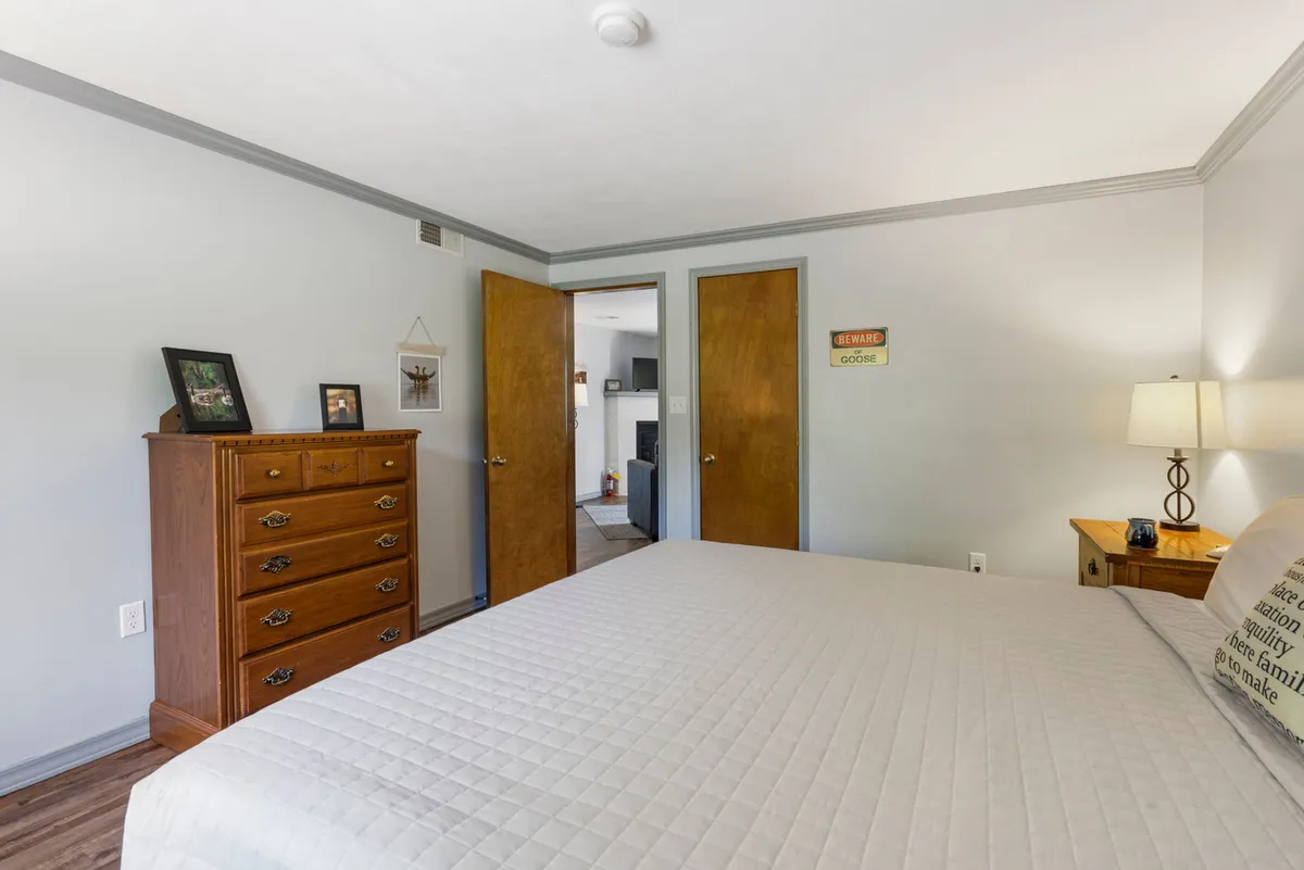 A tranquil bedroom with a neatly made bed, a dresser, and nightstand. Soft, natural light fills the room, creating a serene atmosphere ideal for relaxation and privacy.