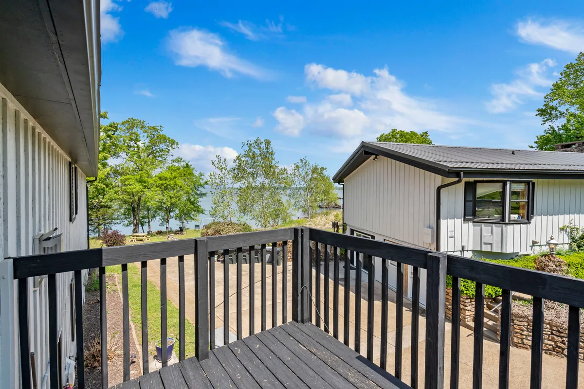 A peaceful balcony scene overlooks the lake and is surrounded by lush greenery, inviting guests to relax and soak in panoramic water views. The vantage point suggests a private, intimate setting ideal for morning coffee or evening relaxation.