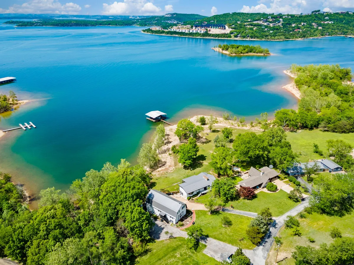This image captures a serene lakeside setting with a dock extending over the water, surrounded by houses and lush trees. The calm lake invites water activities such as boating, fishing, and kayaking. The scene hints at sunset with warm light reflecting on the water, emphasizing relaxation and connection to nature.